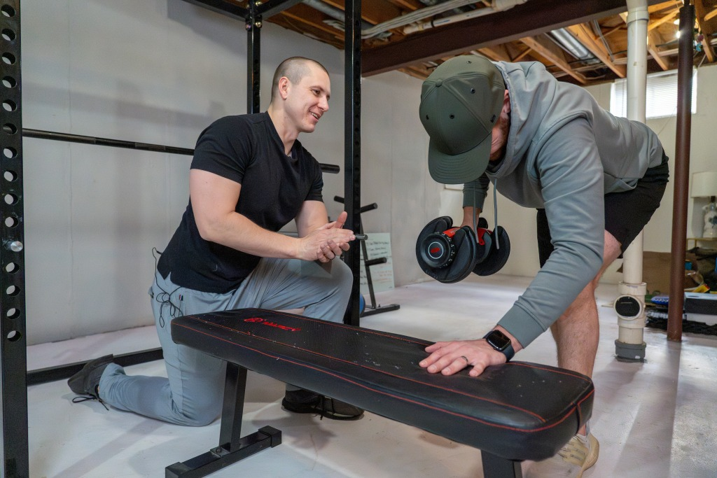 Patrick coaching a member through a dumbbell row